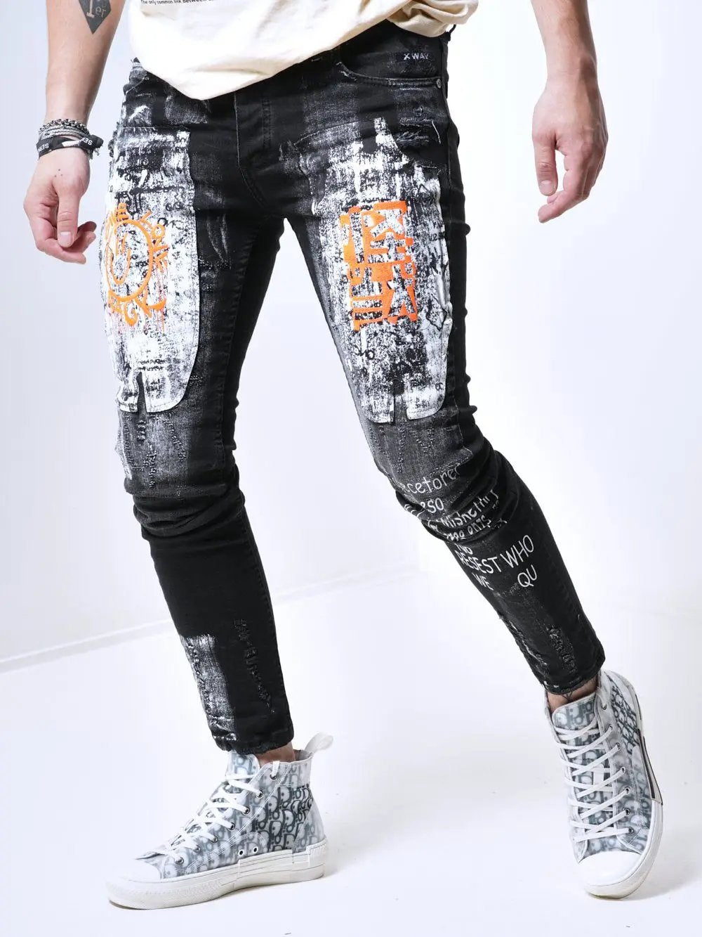 A man wearing a pair of SIXTY SIX jeans with graffiti on them.