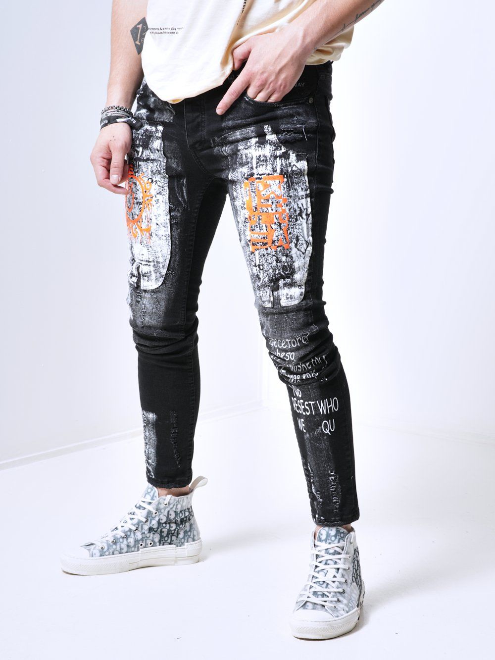 A man wearing a pair of SIXTY SIX jeans with graffiti on them.