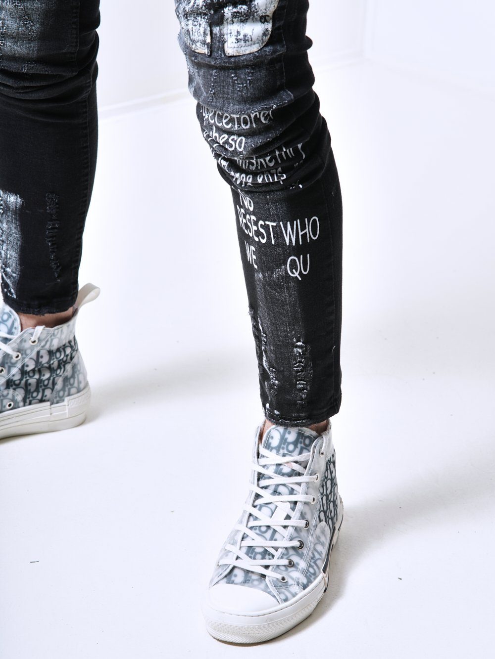 A man wearing a pair of SIXTY SIX jeans with writing on them.