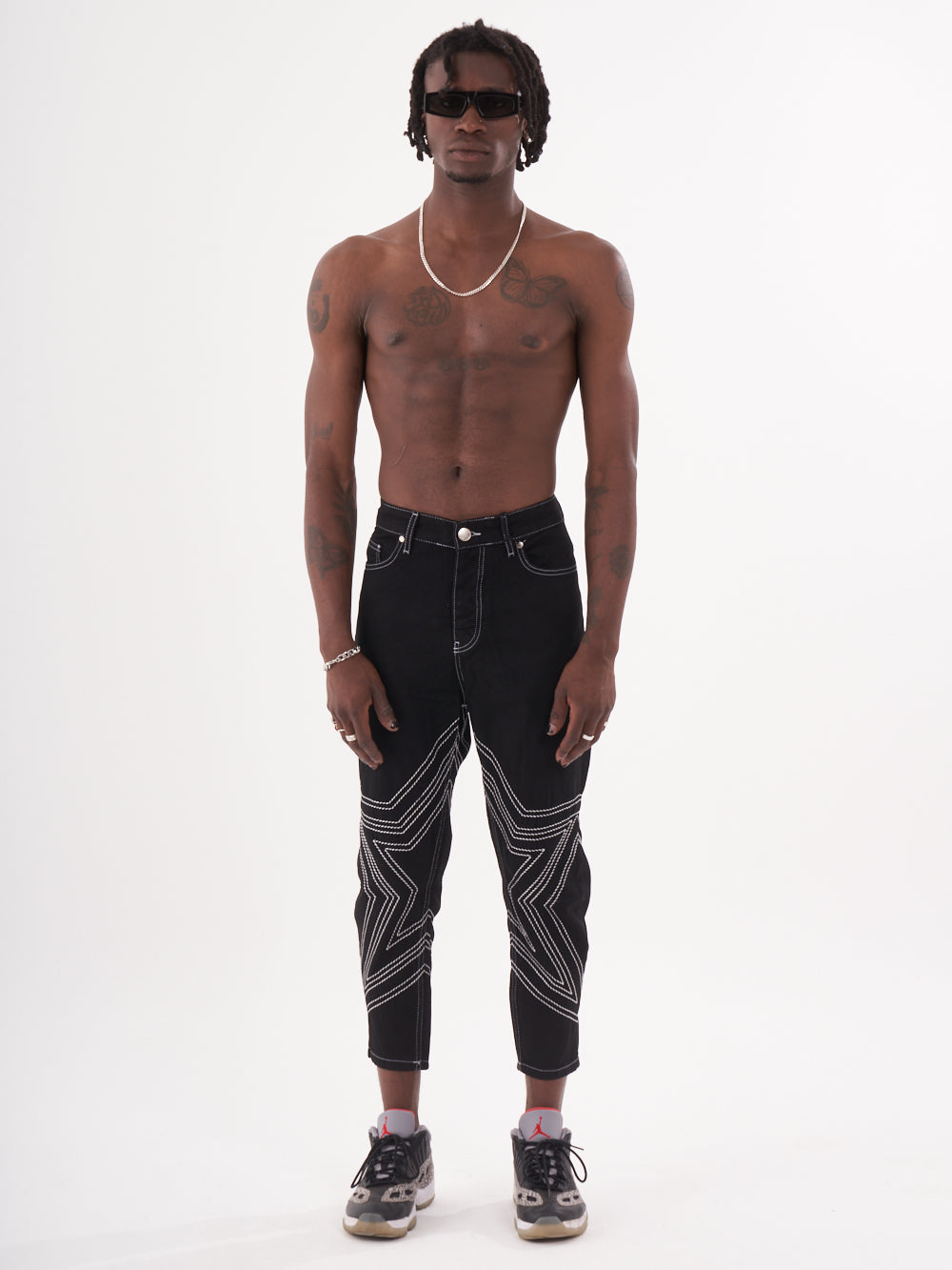 A man wearing black jeans and a STARDOM tee shirt.