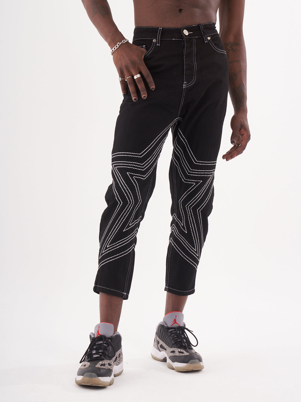 A man wearing a pair of black STARDOM jeans.