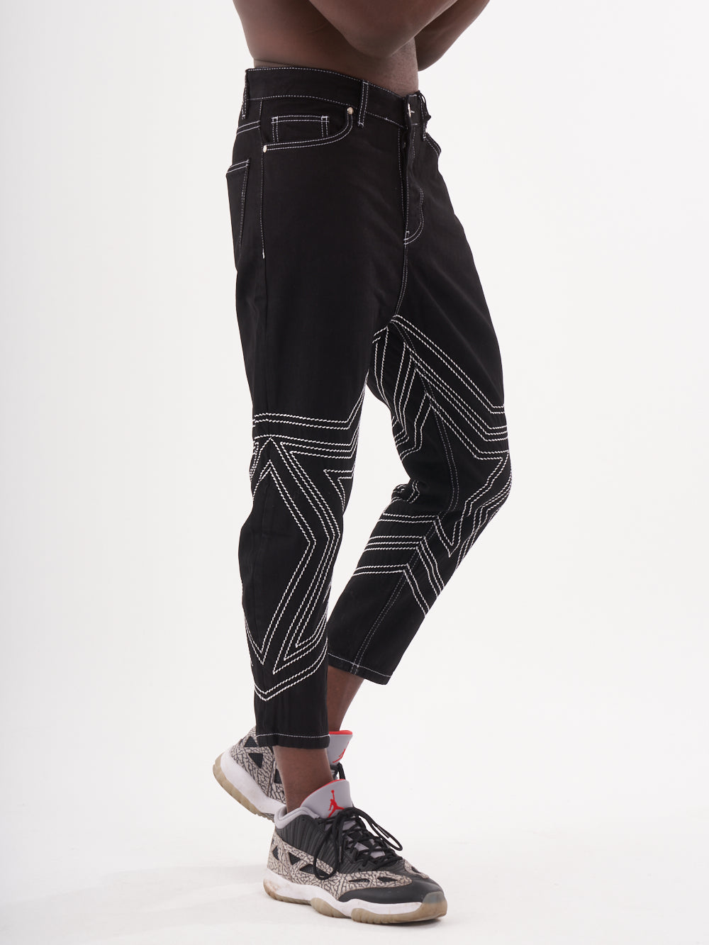 A man wearing a pair of black STARDOM jeans and a white t-shirt.