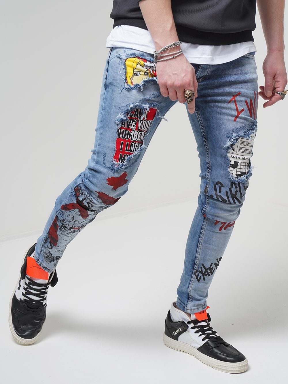 A man wearing a pair of BANKSY jeans with graffiti on them.