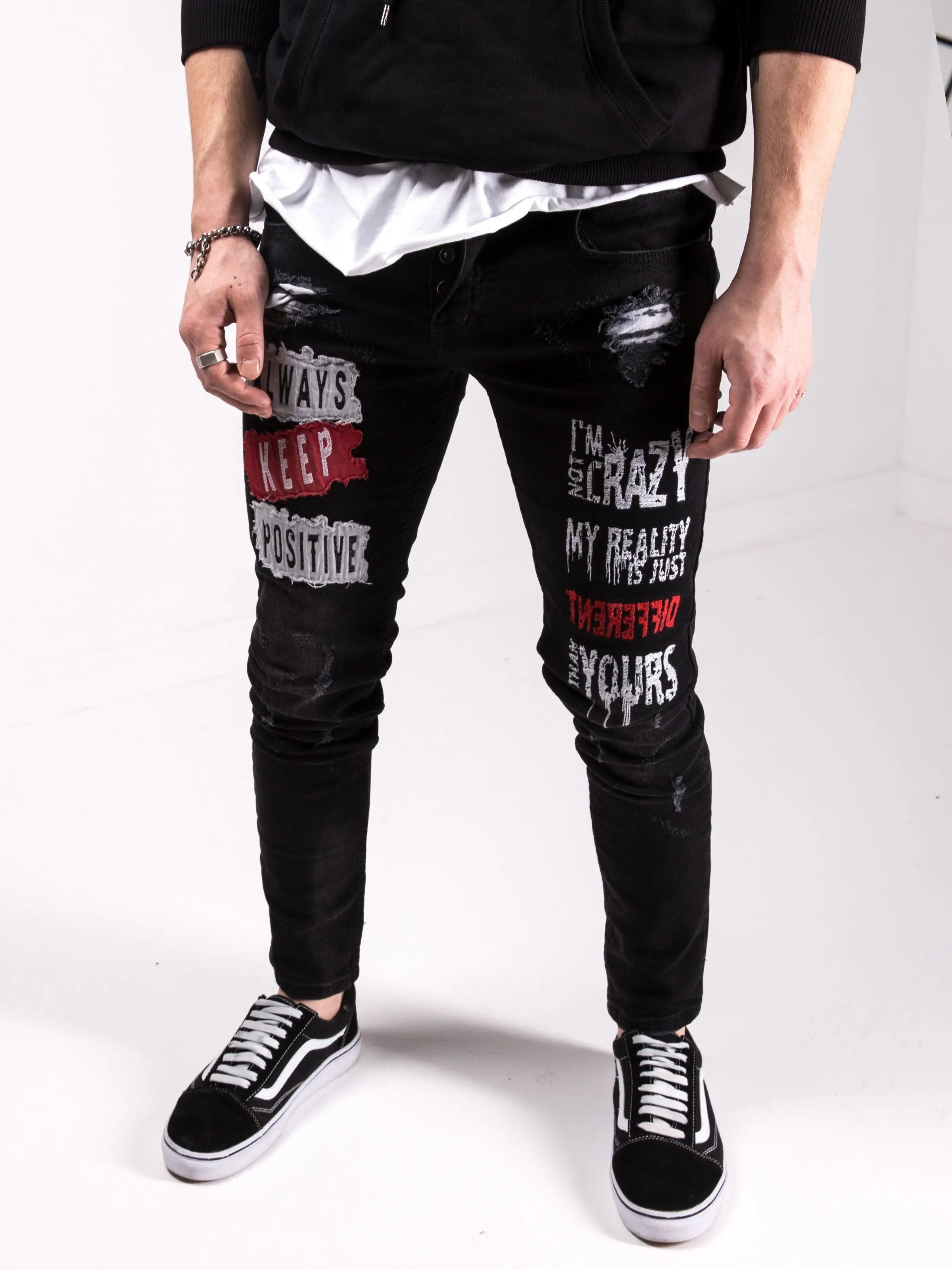 A man wearing ripped jeans and an I'M NOT CRAZY hoodie.