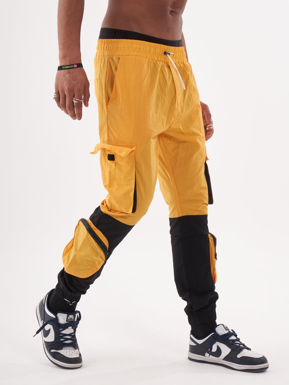 A man wearing RENEGADE | YELLOW cargo pants and black sneakers.