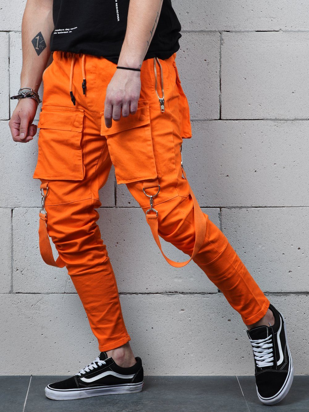 A man wearing ORANGE BRONX cargo pants and a black t - shirt.