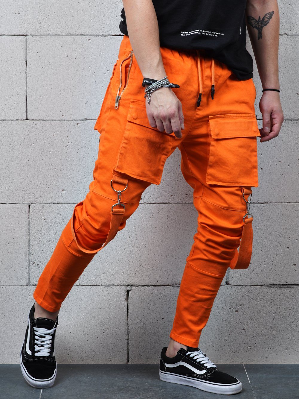 A man wearing ORANGE BRONX cargo pants and a black t - shirt.