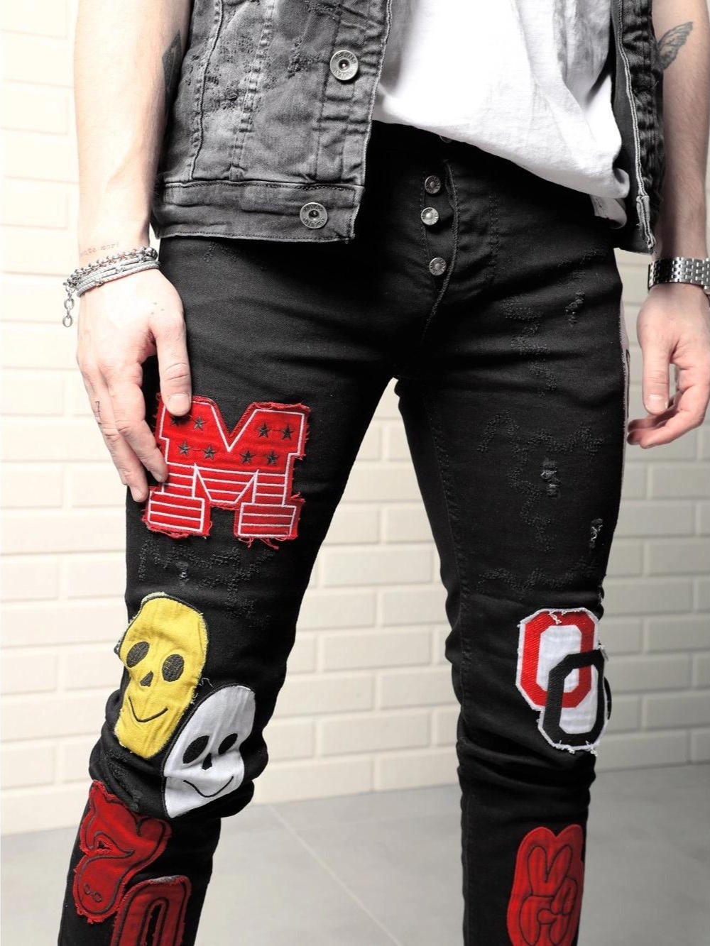 A man wearing a pair of CLOWN CAR with patches on them.