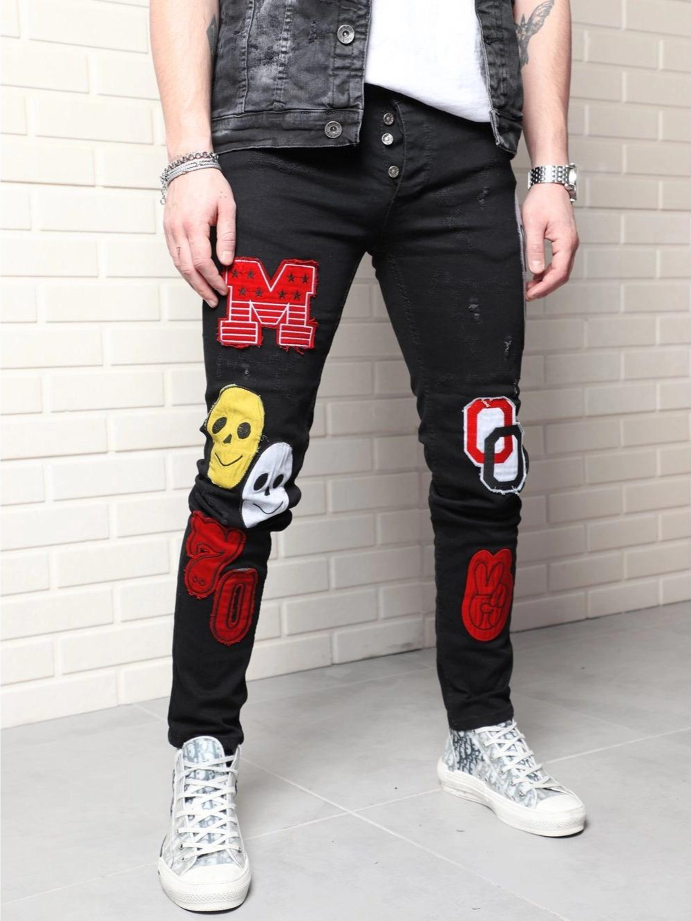 A man wearing a pair of black CLOWN CAR with patches on them.