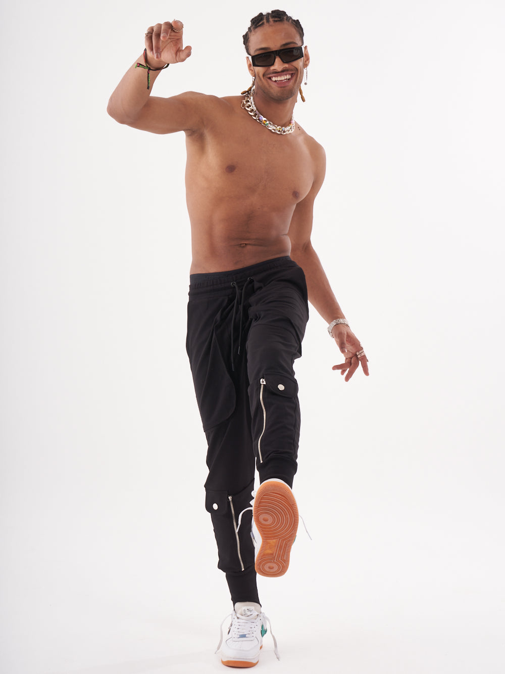 A shirtless man in GUERRILLA | BLACK pants and a pair of sunglasses.