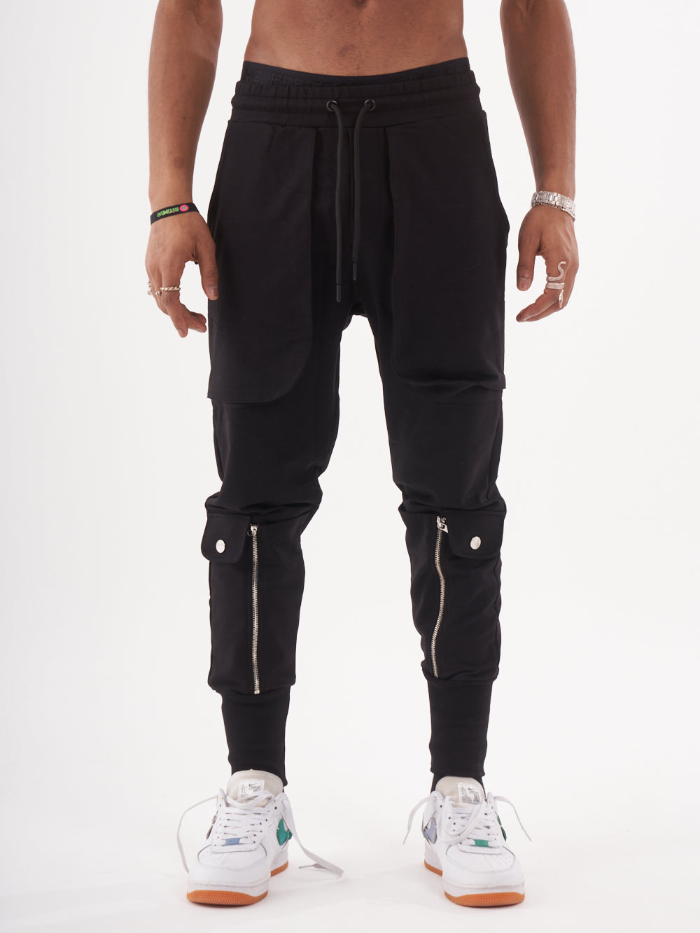 A man wearing GUERRILLA | BLACK jogger pants with zippers.