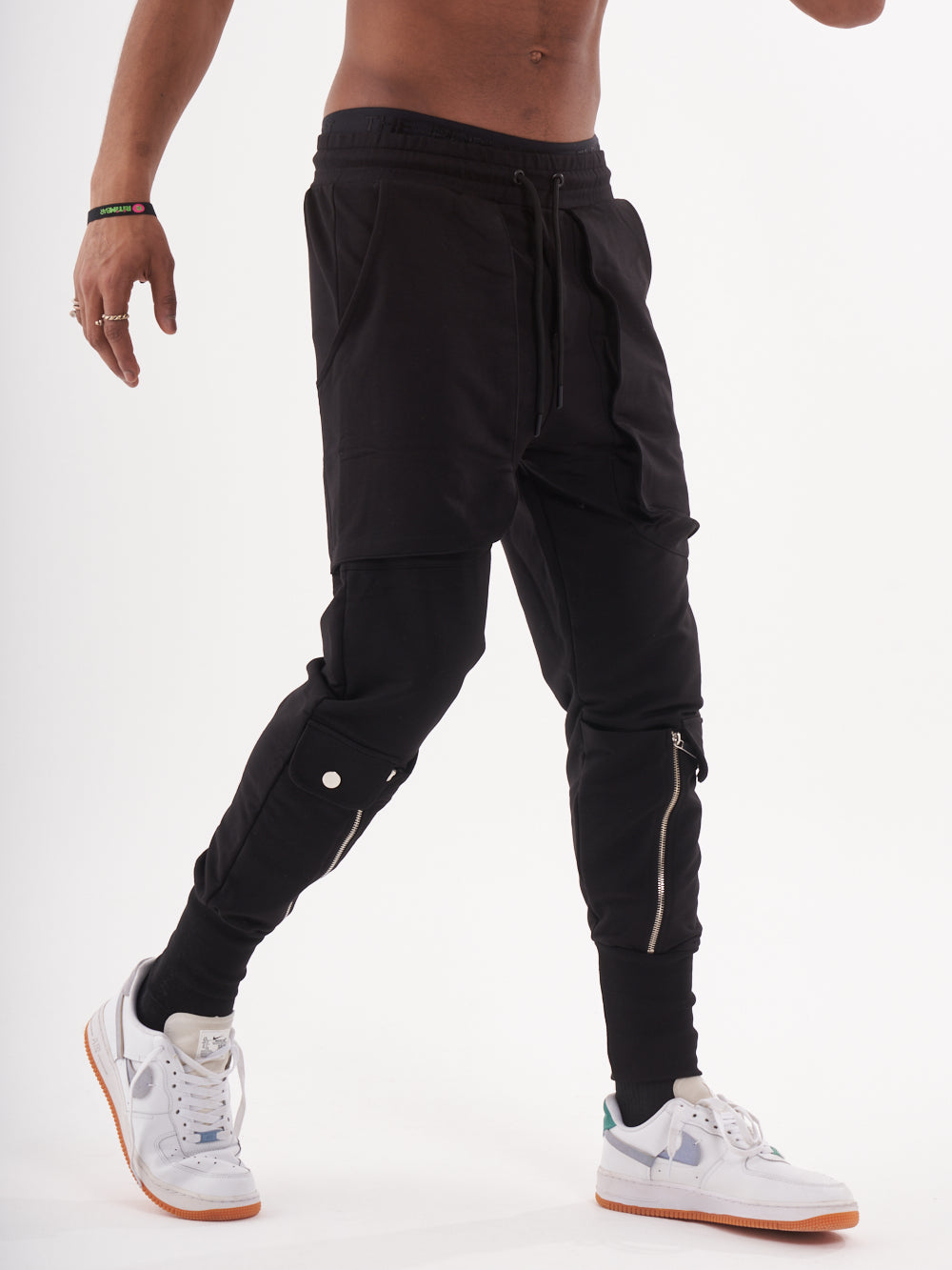 A man wearing GUERRILLA | BLACK joggers and sneakers.