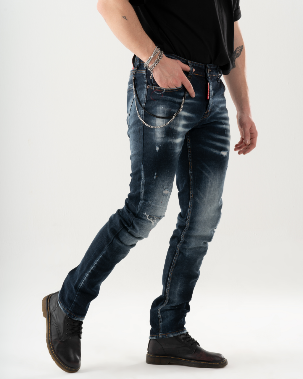 A man wearing skinny jeans and a black shirt is standing in front of a LIGHTNING background.