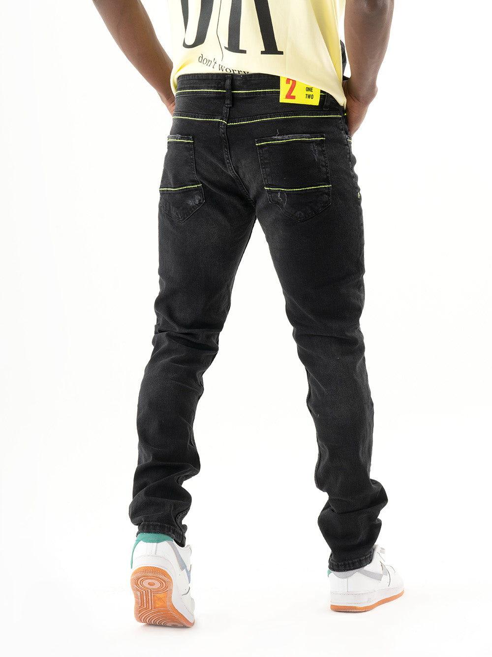 The back of a man wearing TWILIGHT jeans with patches and a yellow t-shirt.