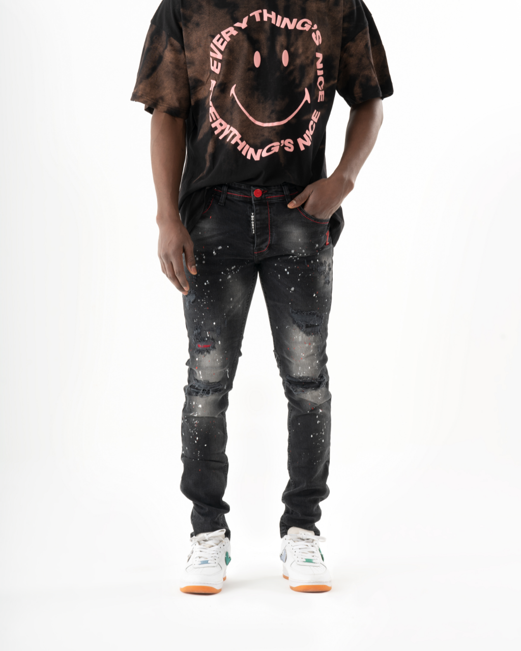 A man wearing a black t-shirt with a HOTSPOT on it and skinny fit jeans.