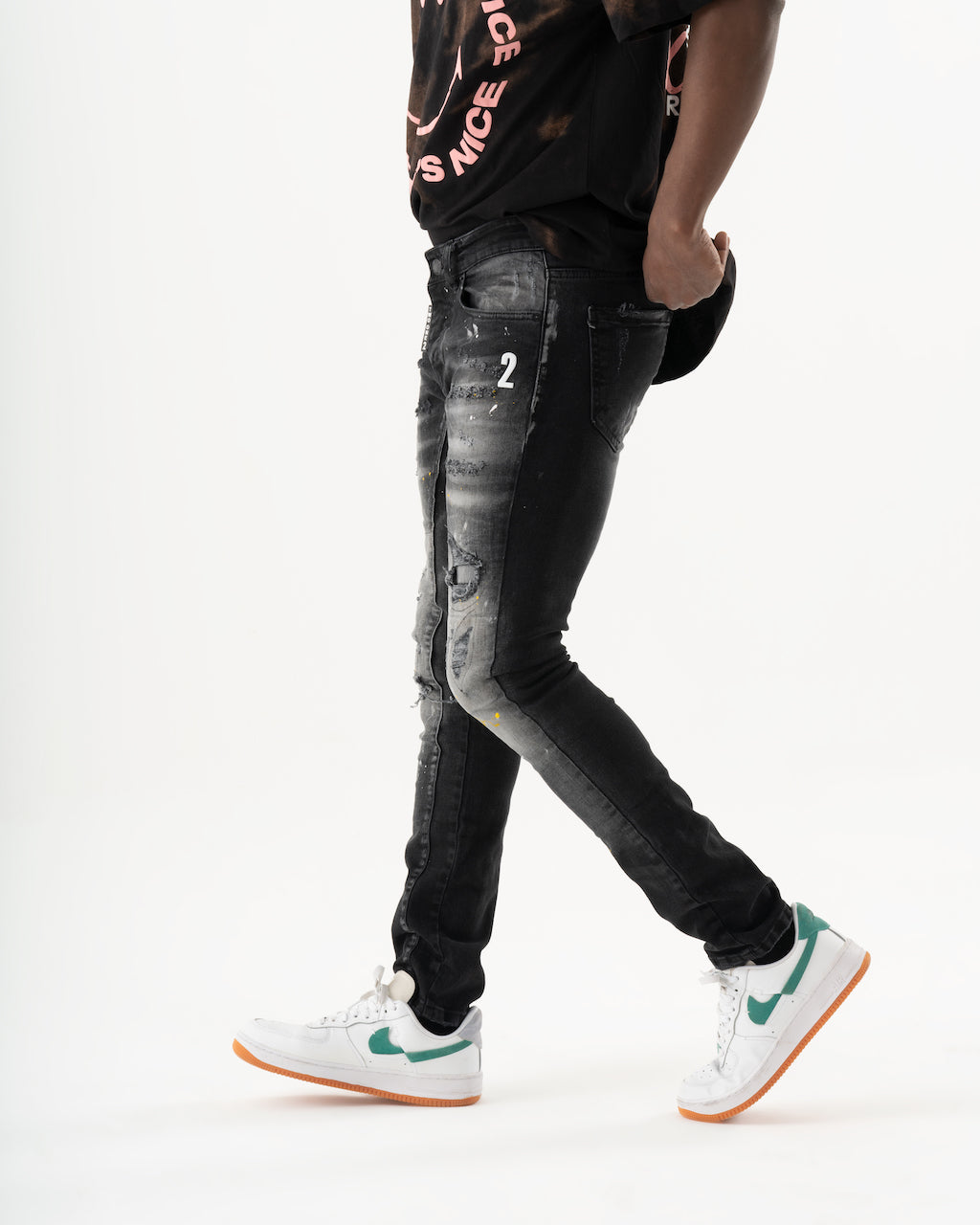 A man wearing ENRAGE skinny fit black jeans made of elastic fabric, giving them a smooth feel.