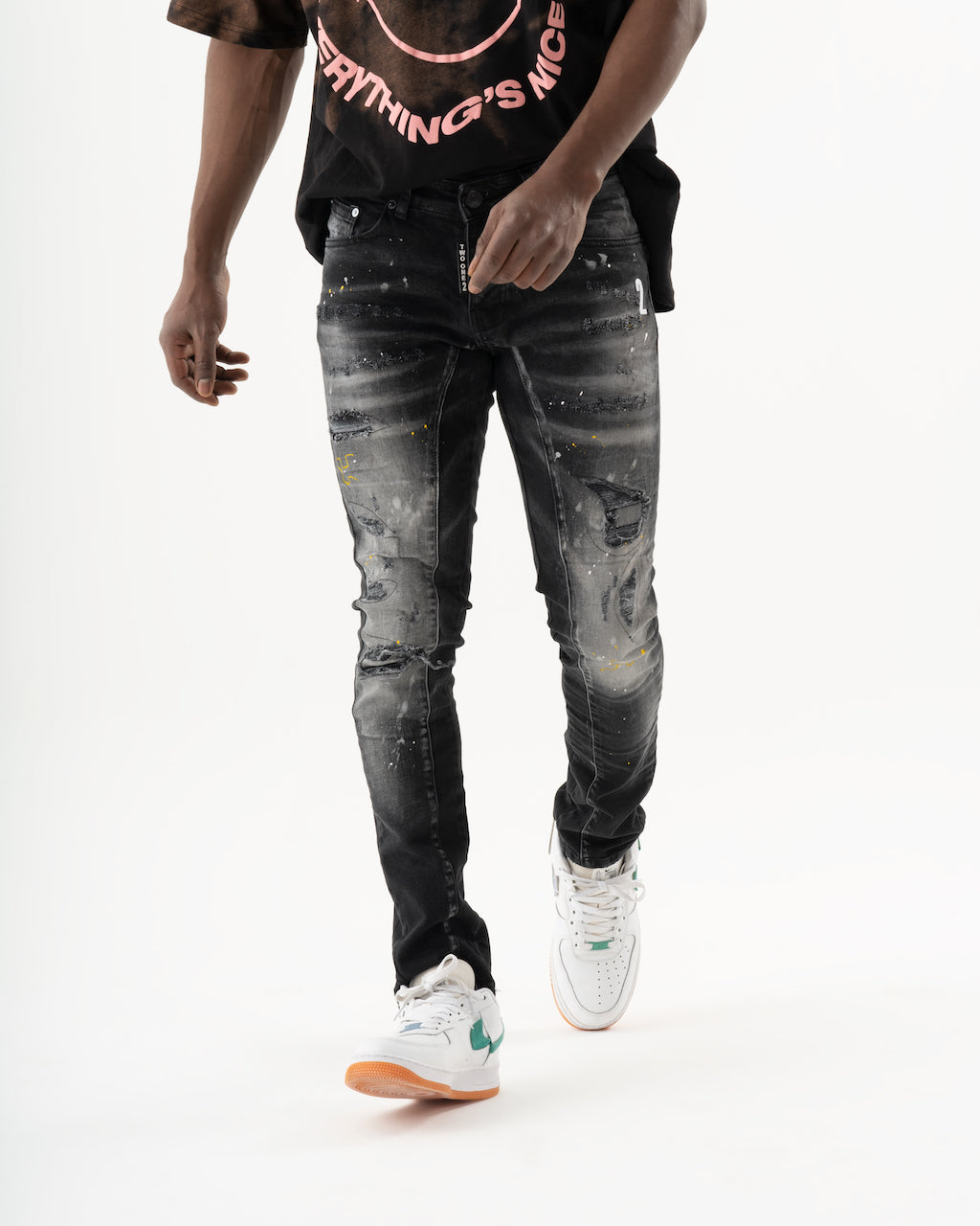 A man wearing black skinny fit jeans and an ENRAGE t-shirt made of elastic fabric, providing a smooth feel.