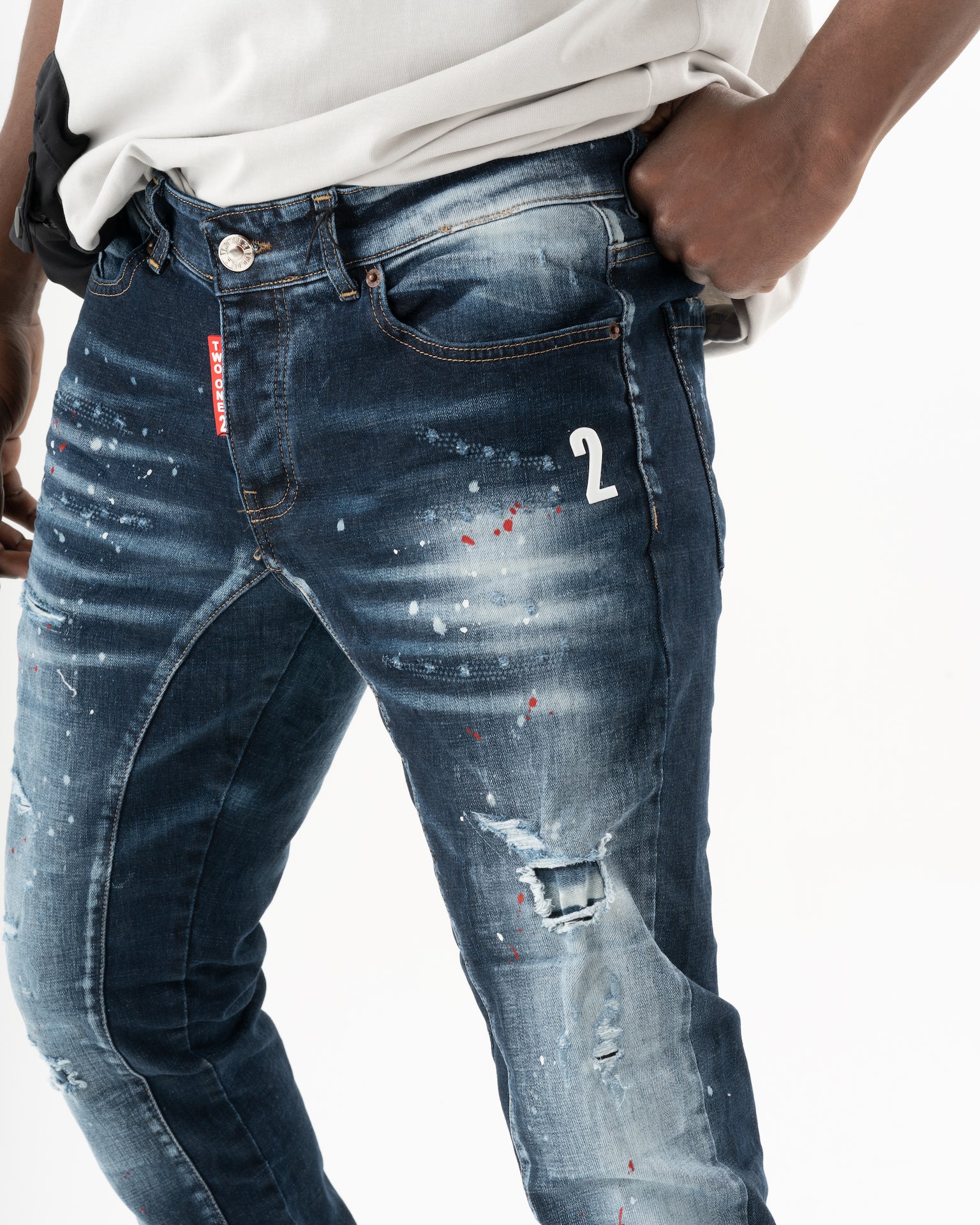 A man wearing a pair of STARLIGHT jeans with paint splatters on them.