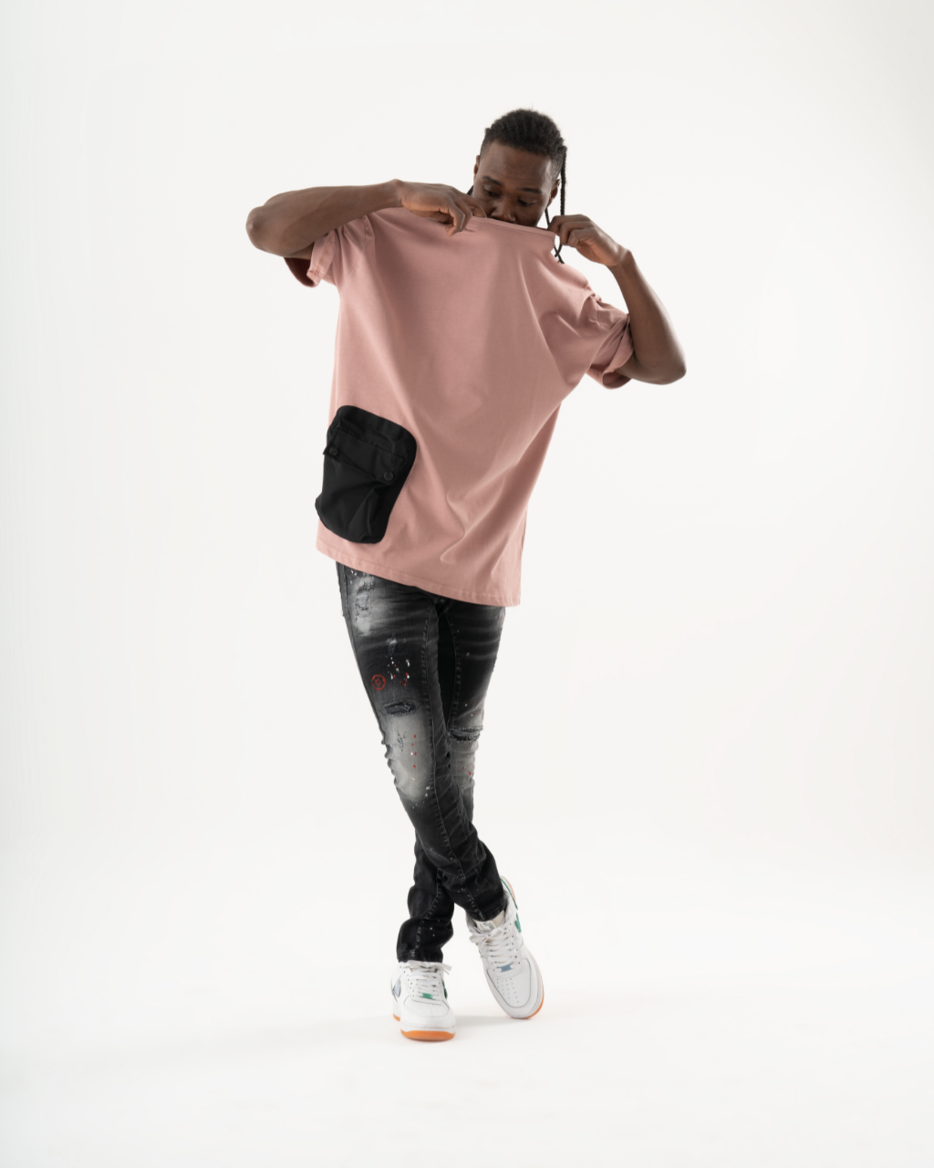 A man wearing ripped skinny fit THUNDERBIRD jeans and a pink t-shirt.