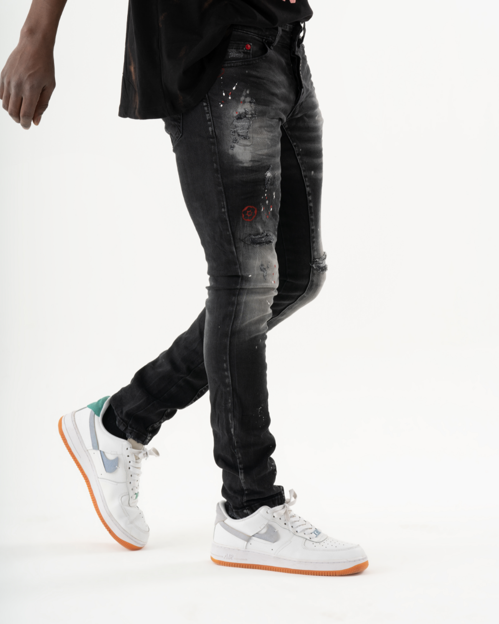 A man wearing ripped black jeans and a white THUNDERBIRD.