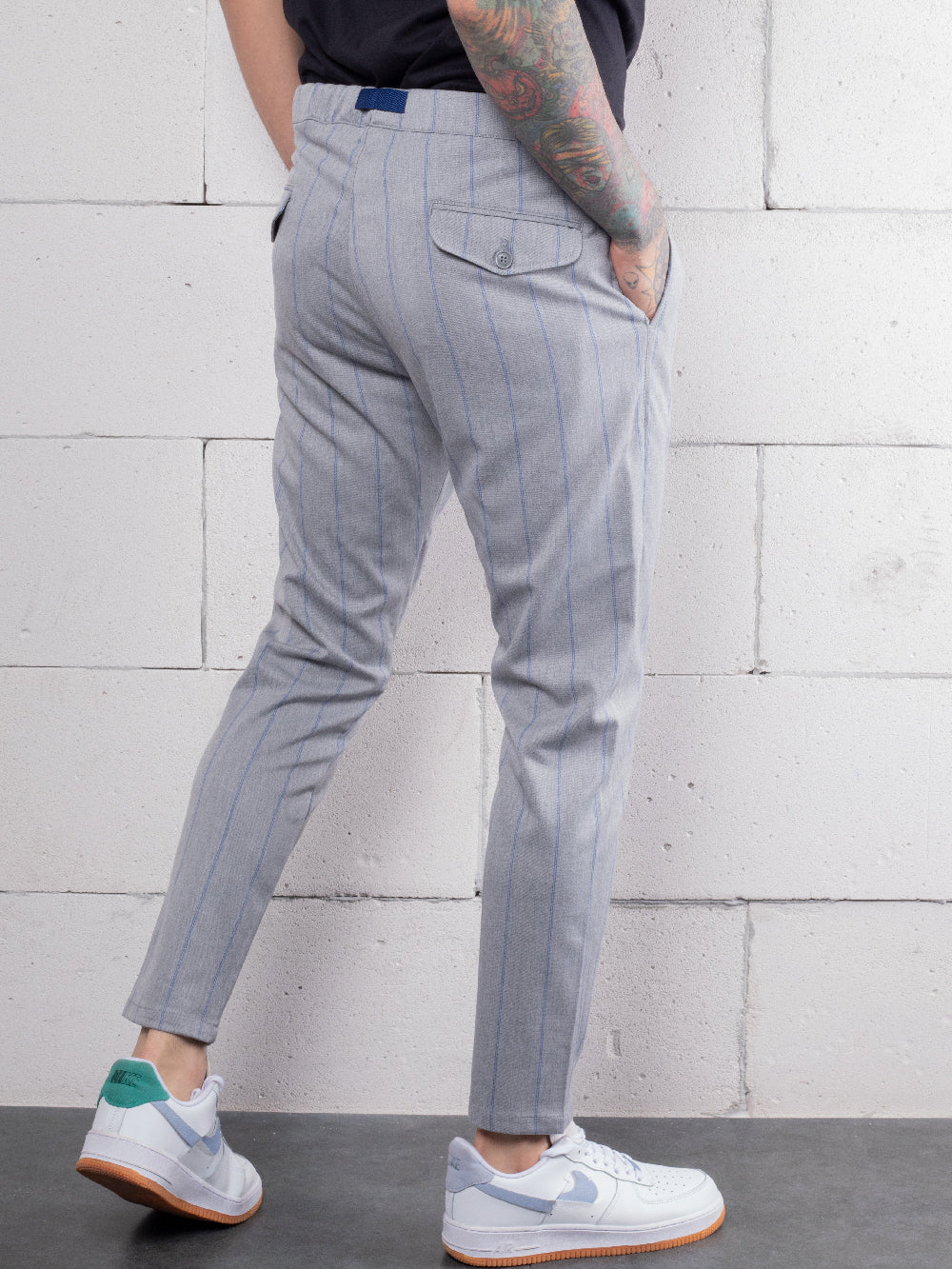A man with tattoos wearing RODEO DRIVE PANTS and sneakers made from premium Italian fabric.