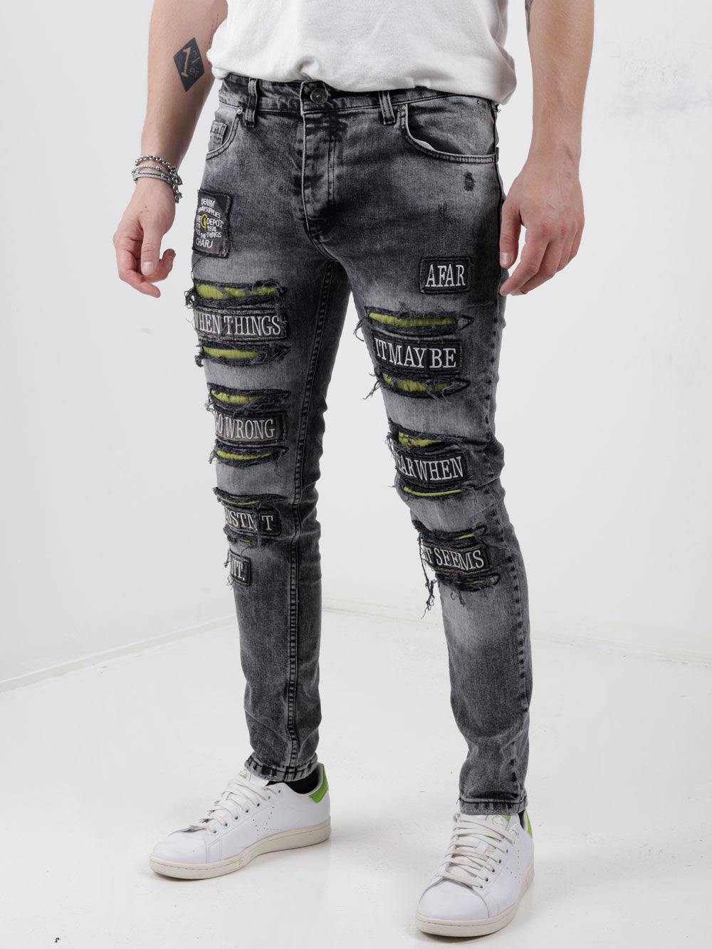 A man wearing IMPROPER jeans and a white t - shirt.