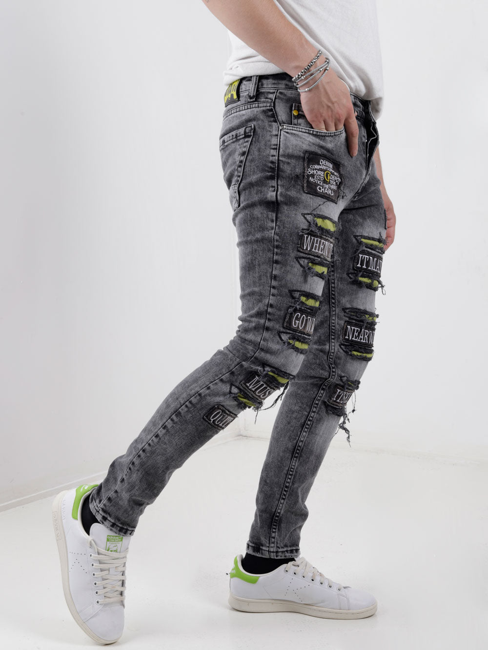 A man wearing IMPROPER jeans and a white t - shirt.