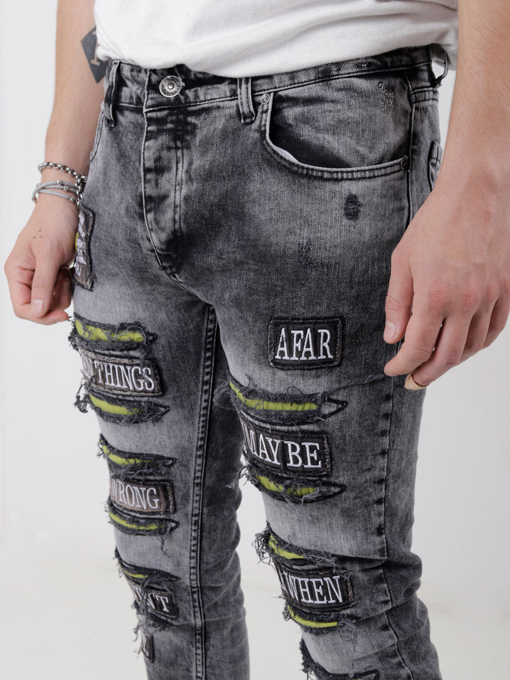 A man wearing a pair of IMPROPER with patches on them.