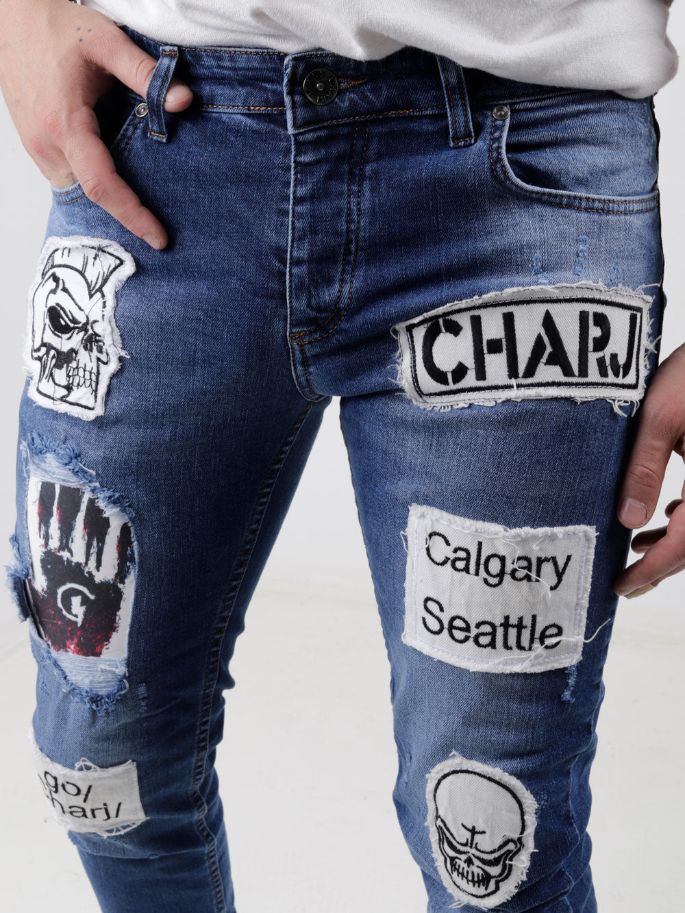 A man wearing a pair of HEADSTONE jeans with patches on them.