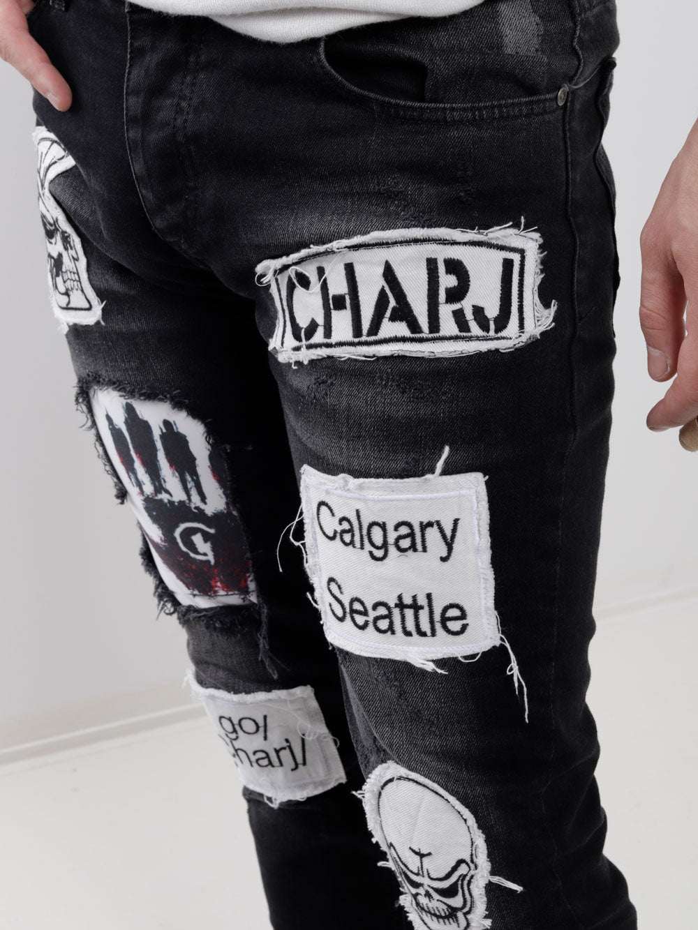 A man wearing a pair of BLACK HEADSTONE with patches on them.