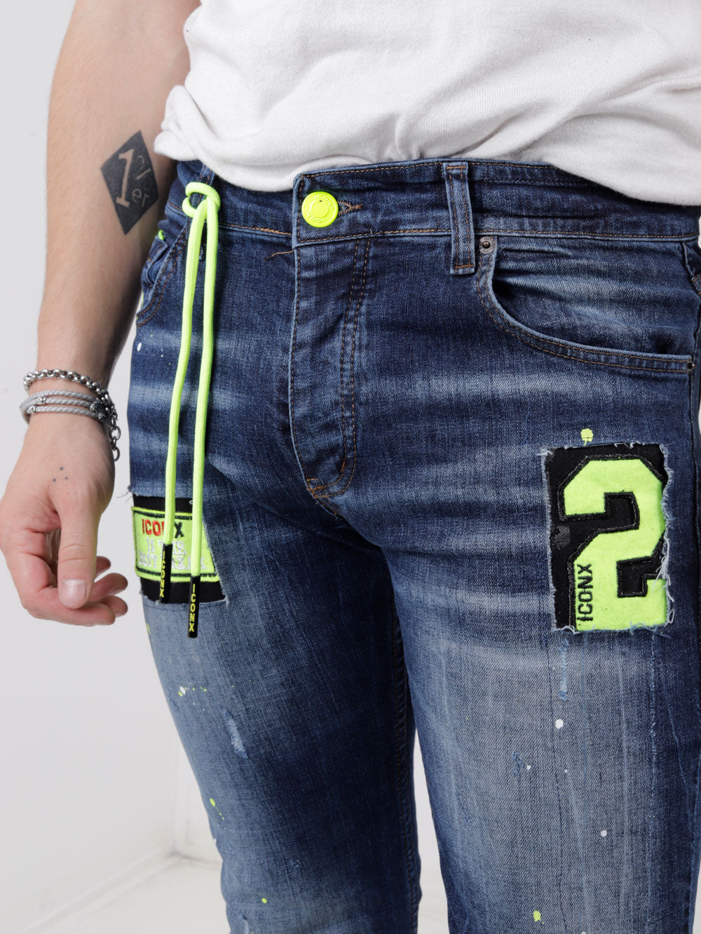 A man wearing a pair of Phosphorus jeans with a number on them.