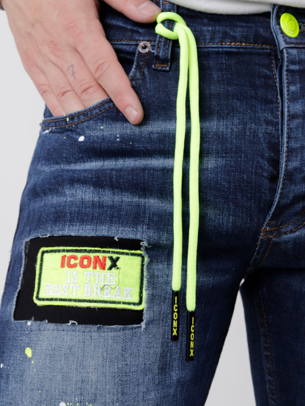 A man is wearing a pair of PHOSPHORUS with neon yellow zippers.