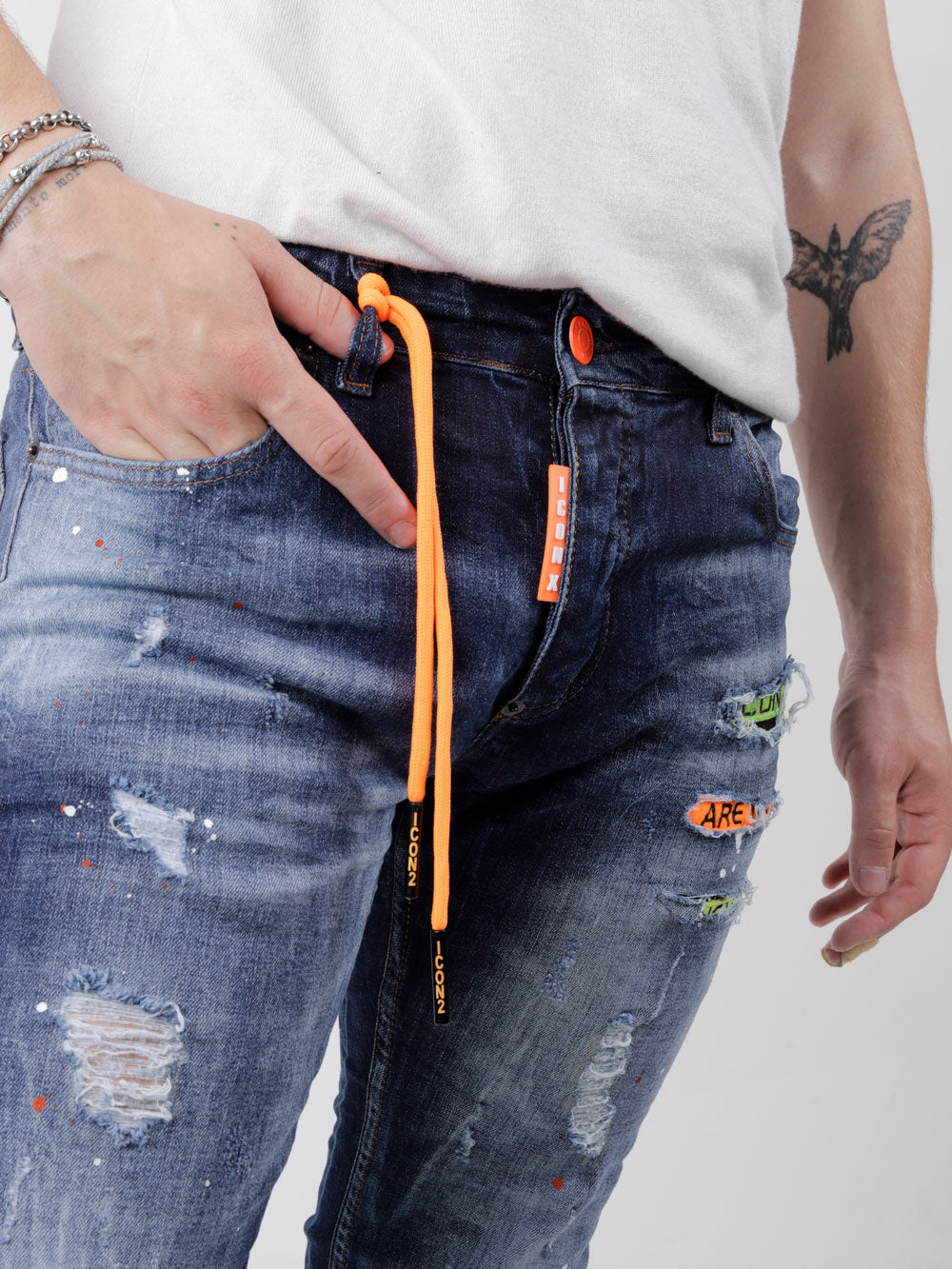 A man is wearing GRAPHITE jeans with an orange belt.