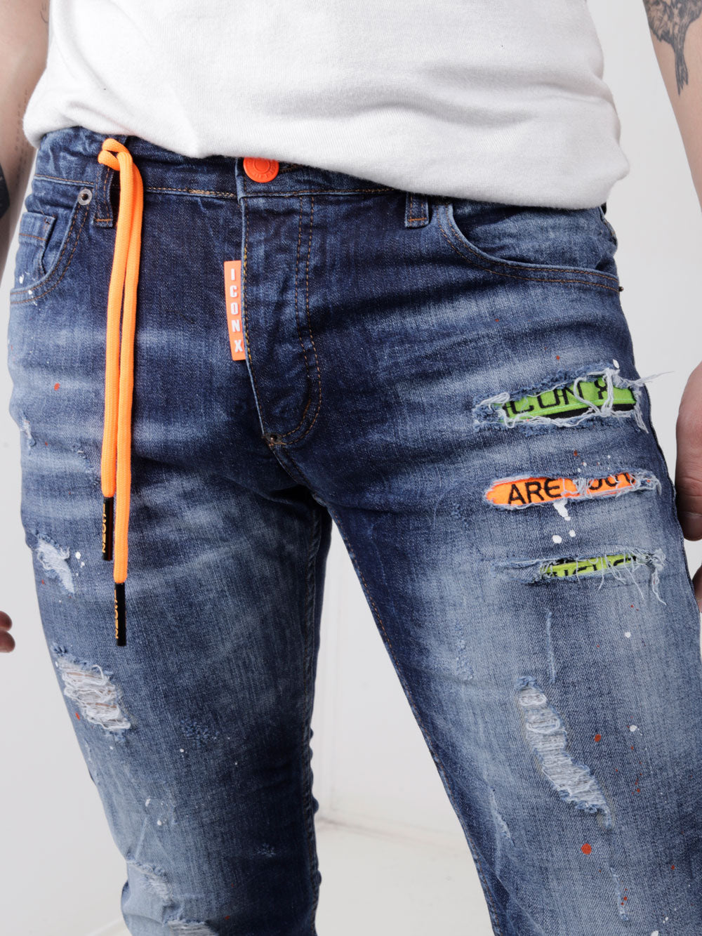 A man wearing ripped GRAPHITE jeans with orange stripes.