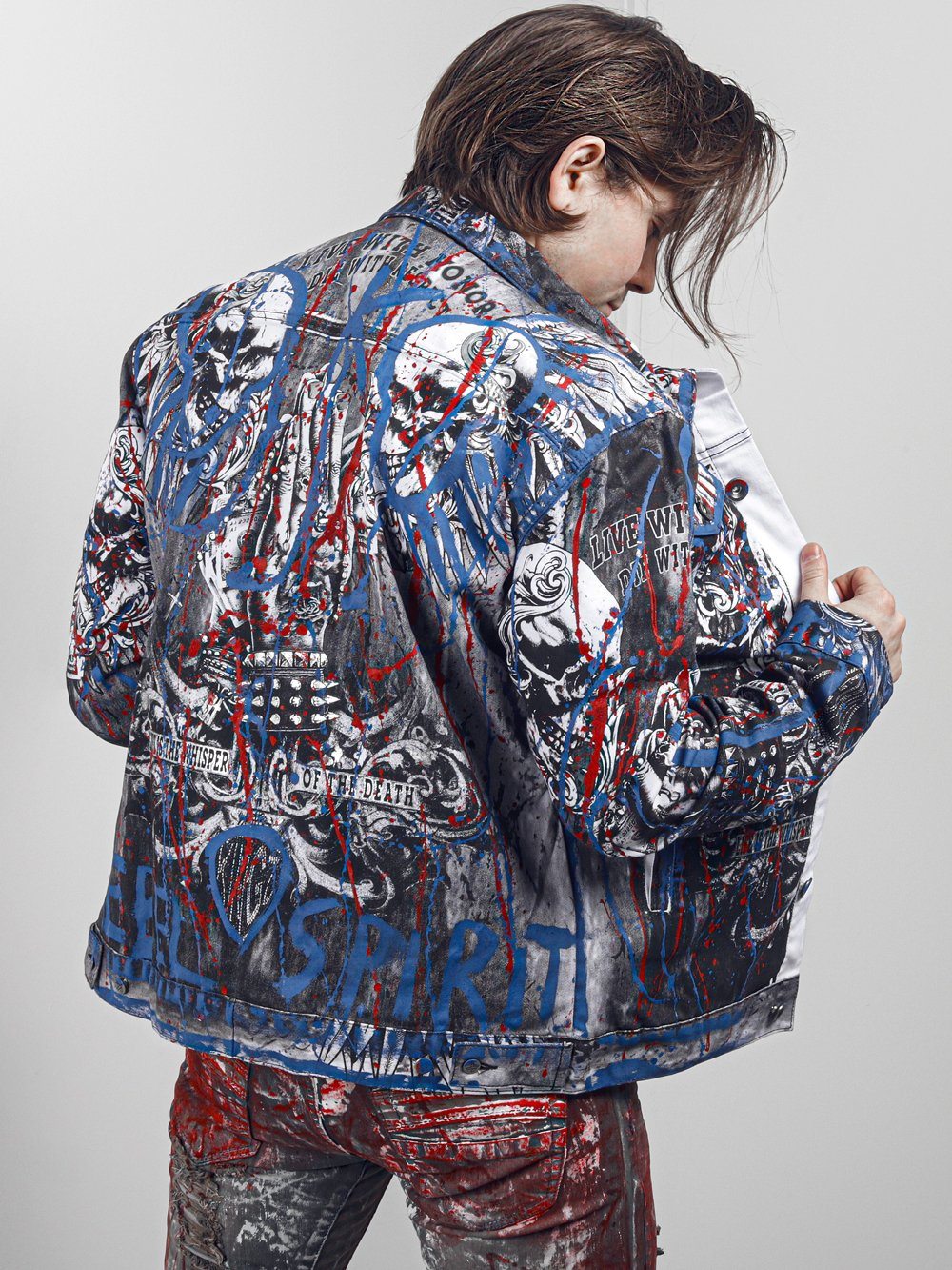 A man wearing a LA VIDA LOCA jacket with skulls on it.