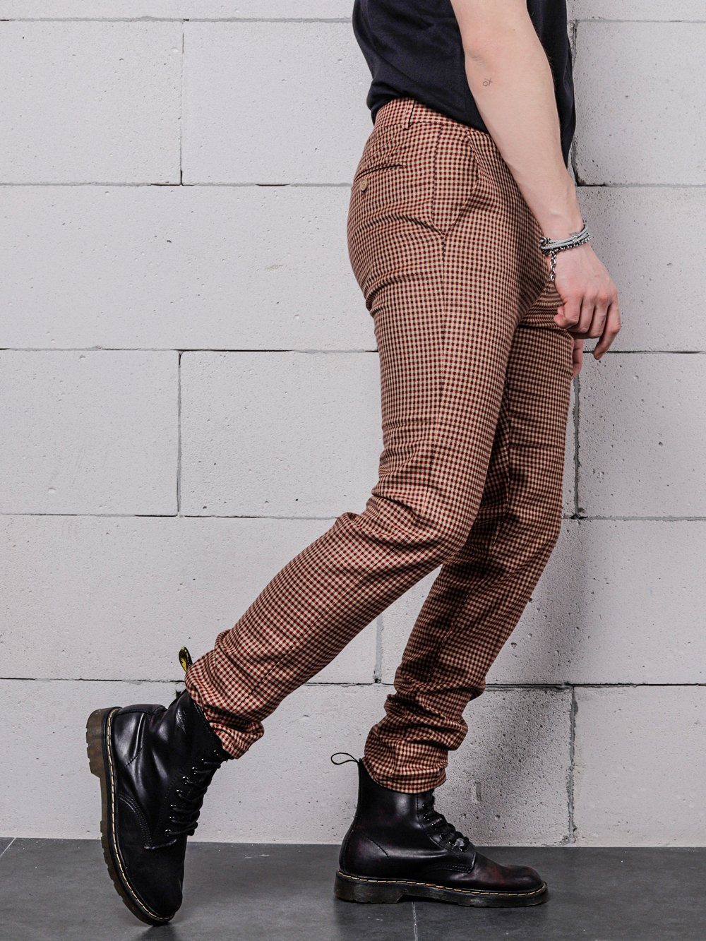 A man in a black shirt and brown pants is leaning against a wall, wearing Java Chip pants.