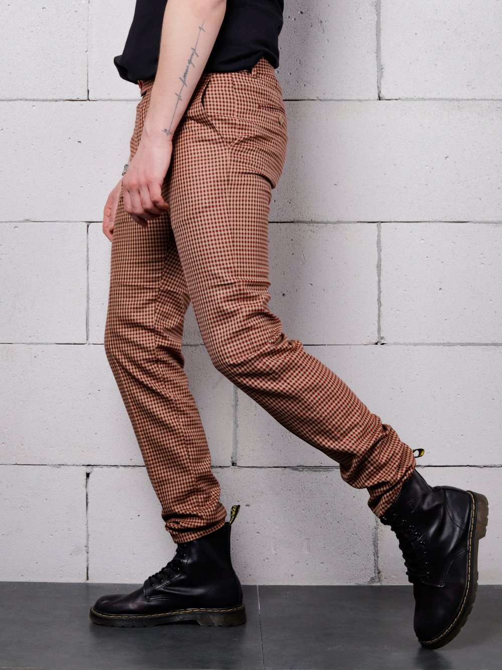 A man in a black shirt and brown pants is leaning against a brick wall wearing JAVA CHIP PANTS.