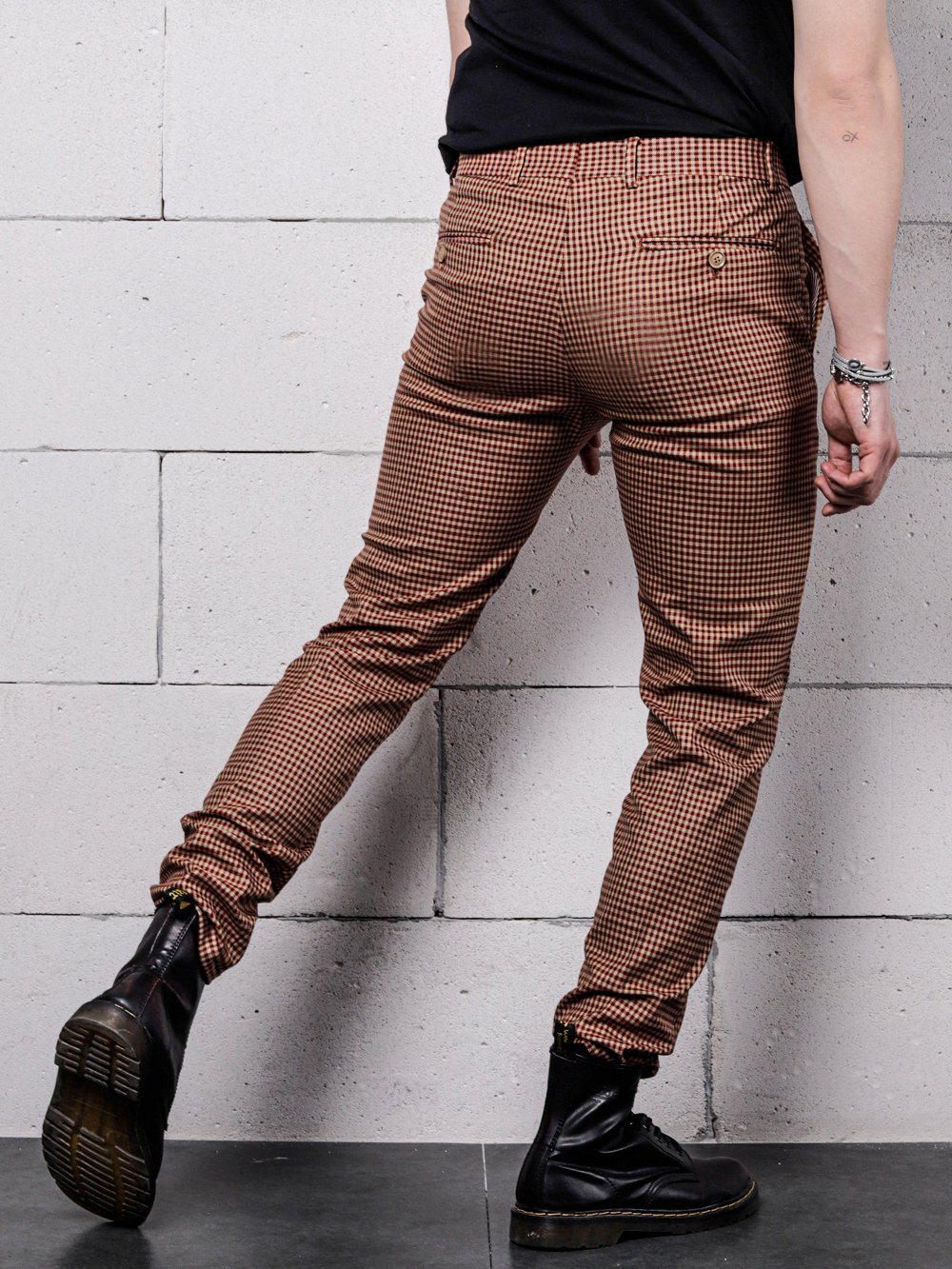 A man in a black shirt and brown pants is leaning against a wall in Java Chip pants.