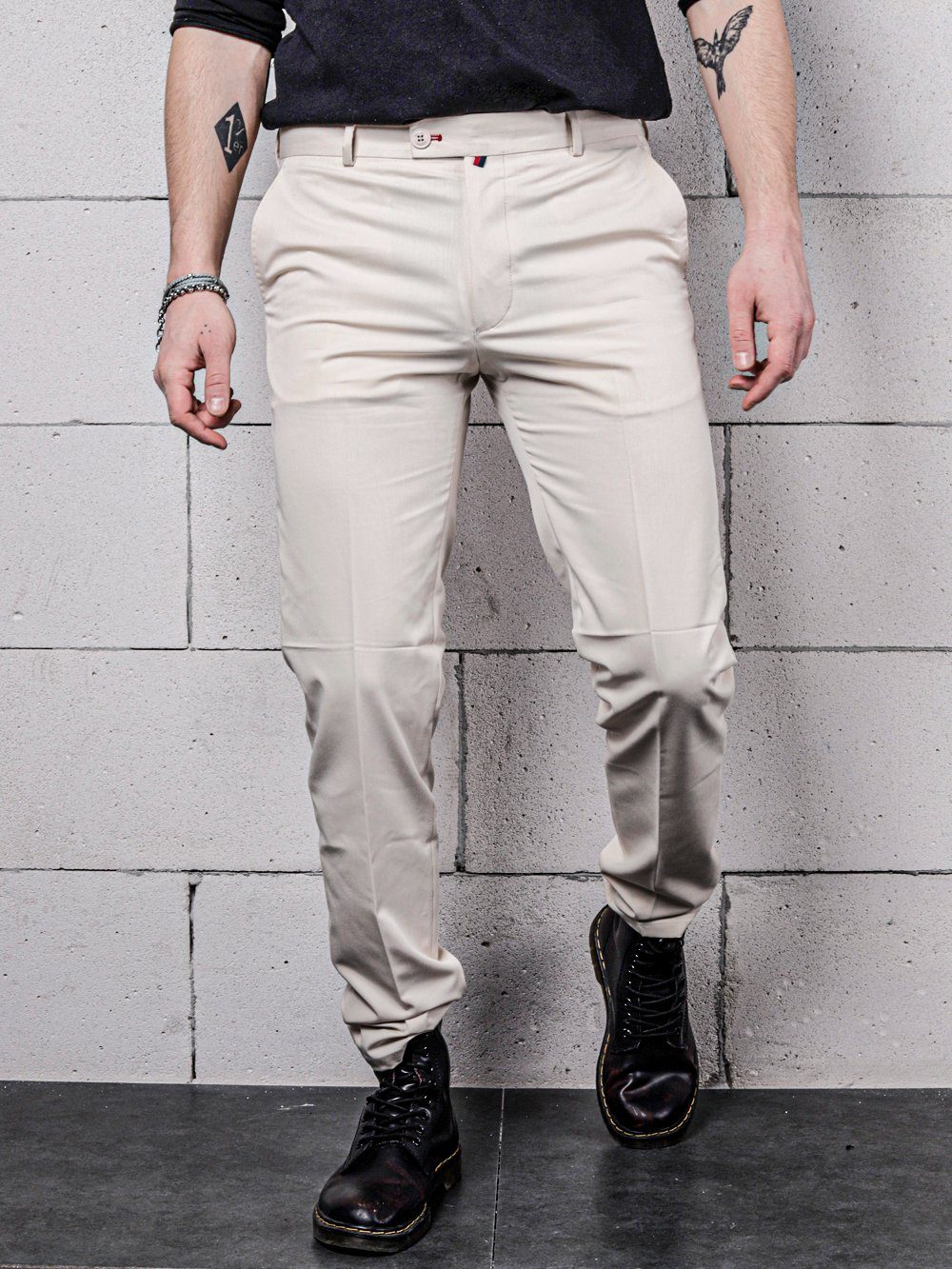 A man in a pair of Vanilla Pants posing in front of a brick wall.