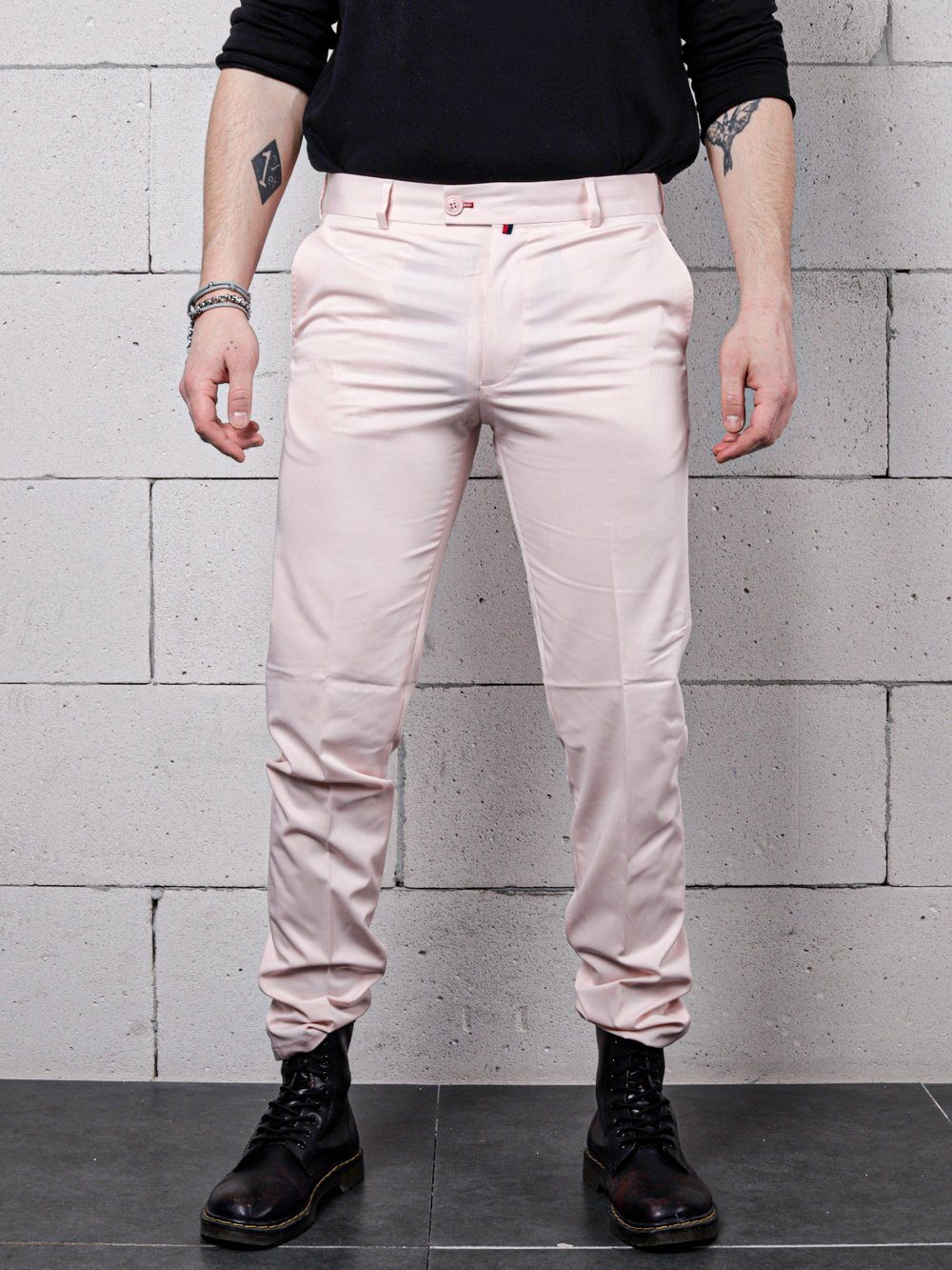 A man in Candy Dust Pants is standing in front of a brick wall.