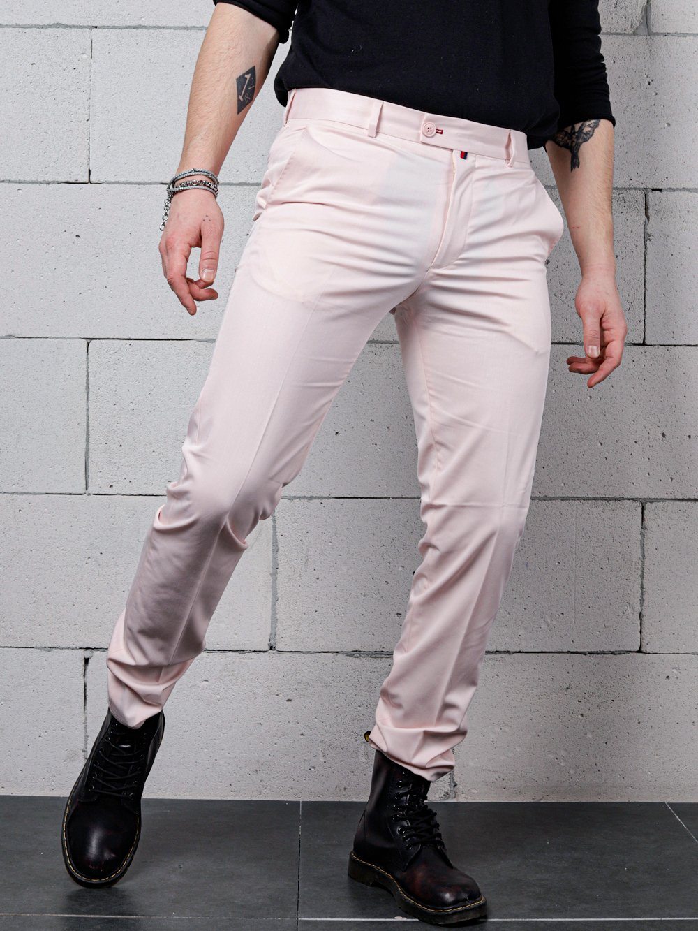 A man in Candy Dust Pants is posing in front of a brick wall.