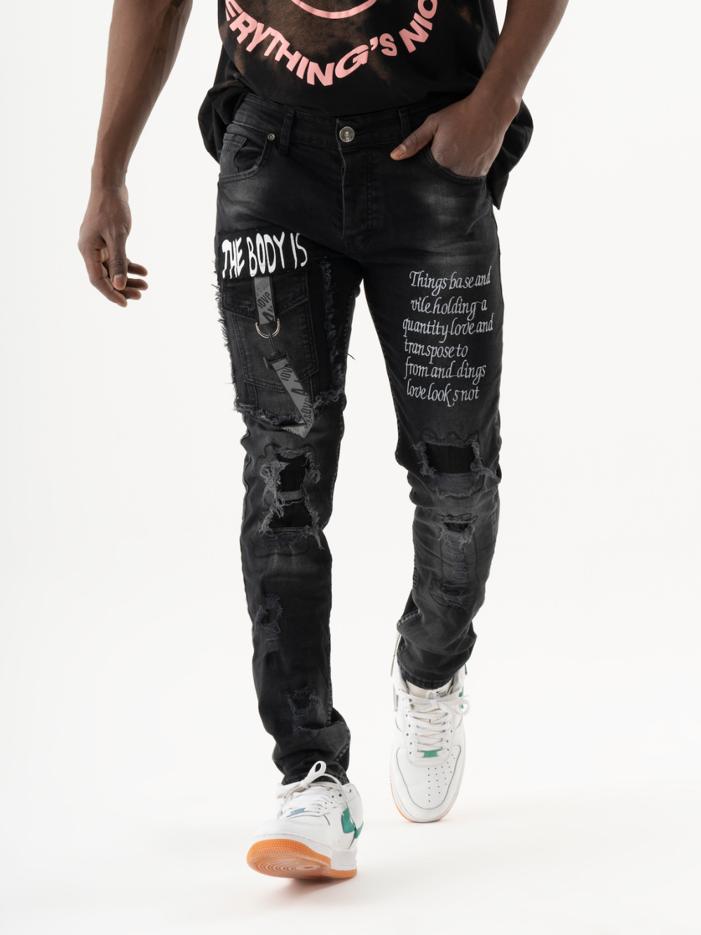 A black man wearing an ONE SOUL t - shirt and jeans.