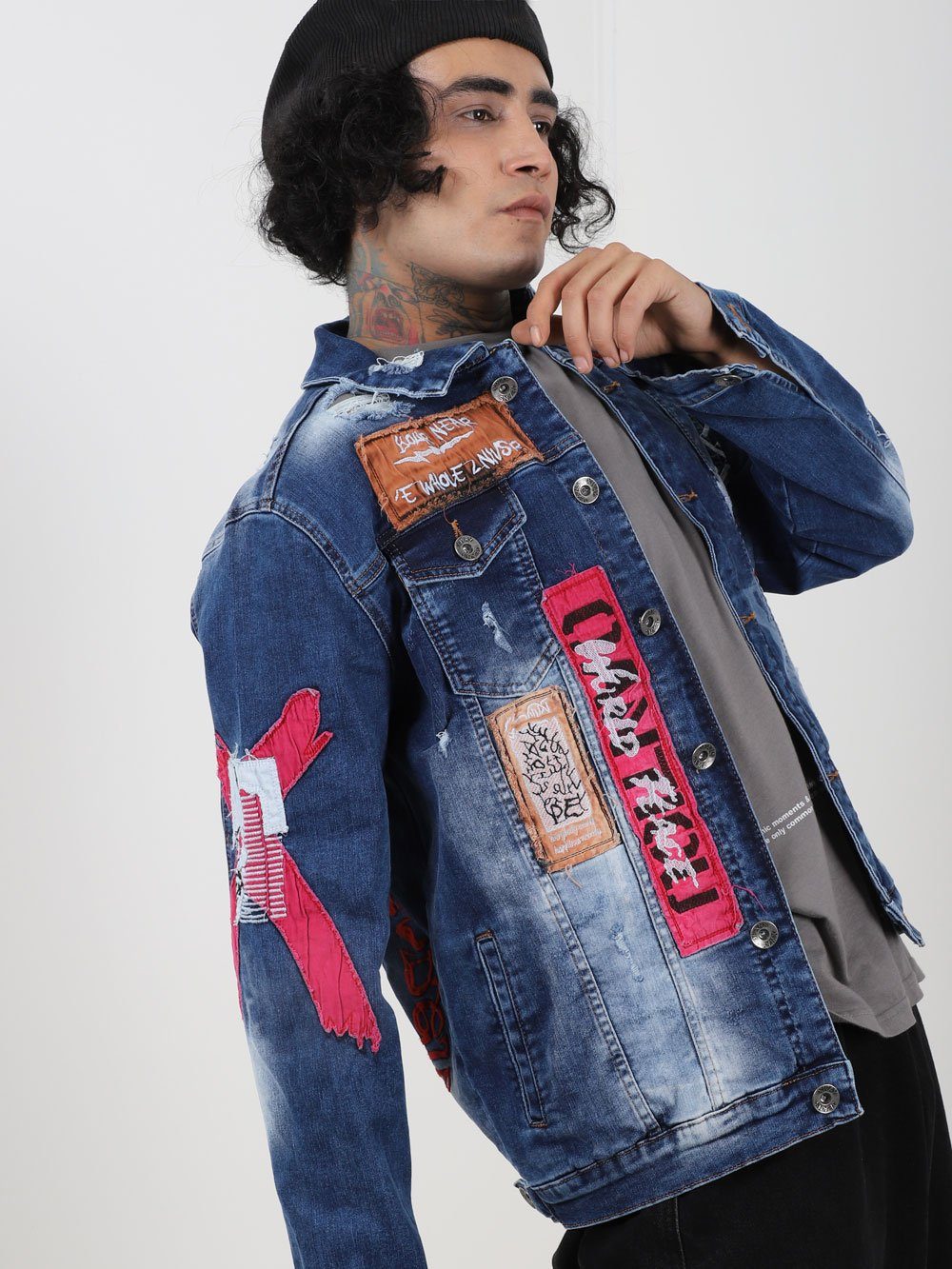 A man wearing THE VETERAN denim jacket with patches on it.