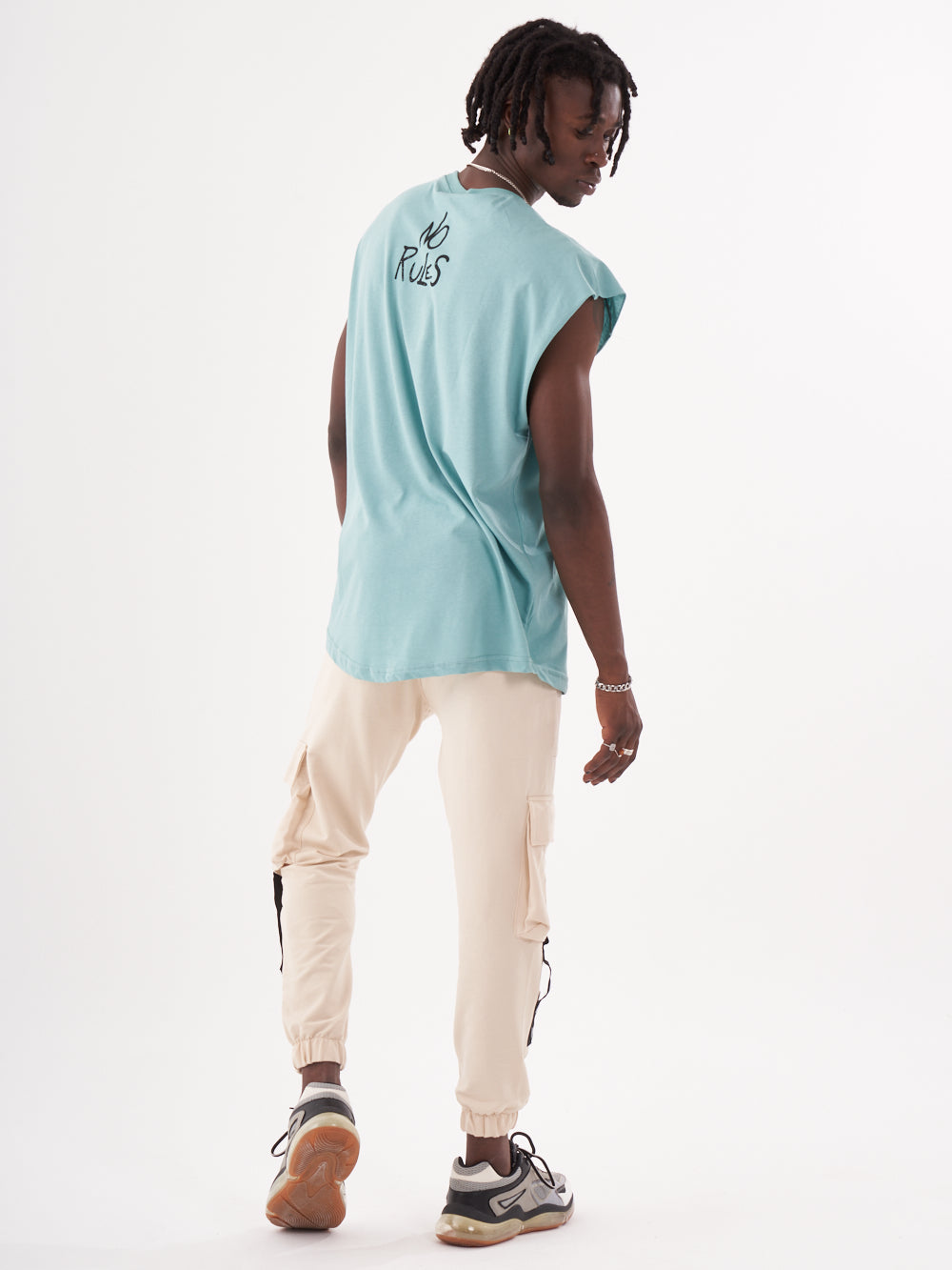 The back of a man wearing a REBELLION T-SHIRT and white joggers.