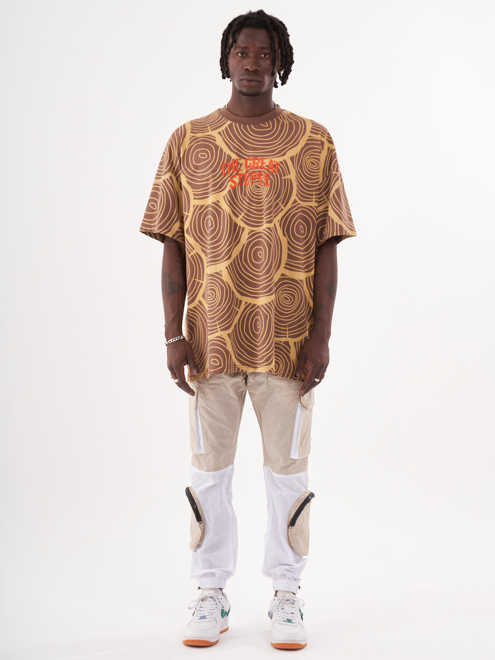A man wearing a STEPPE T-SHIRT and white pants.