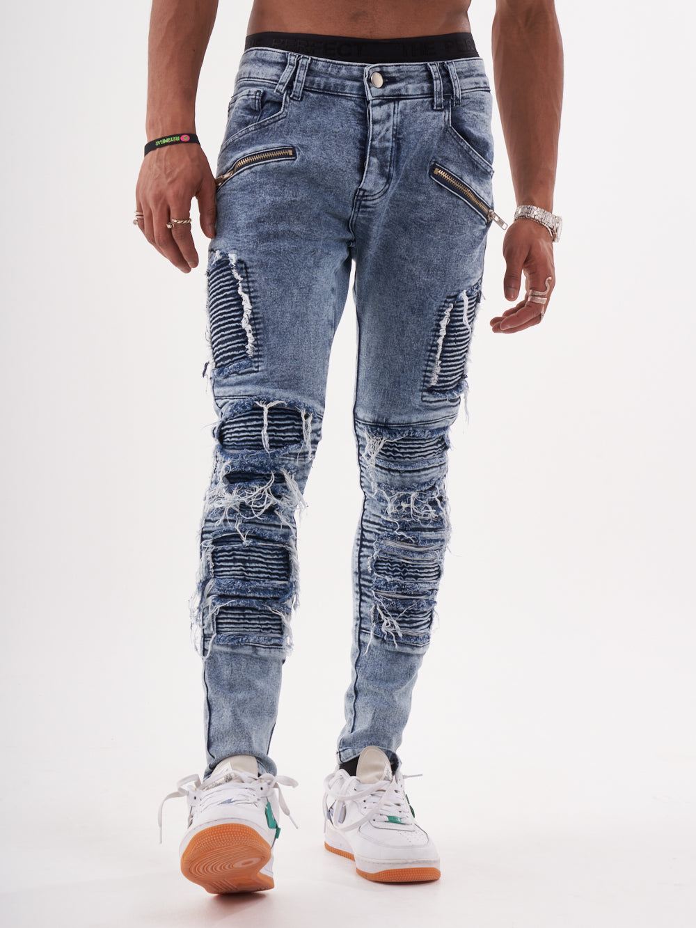 A man wearing ripped jeans and sneakers standing in front of a white background with RADICAL.
