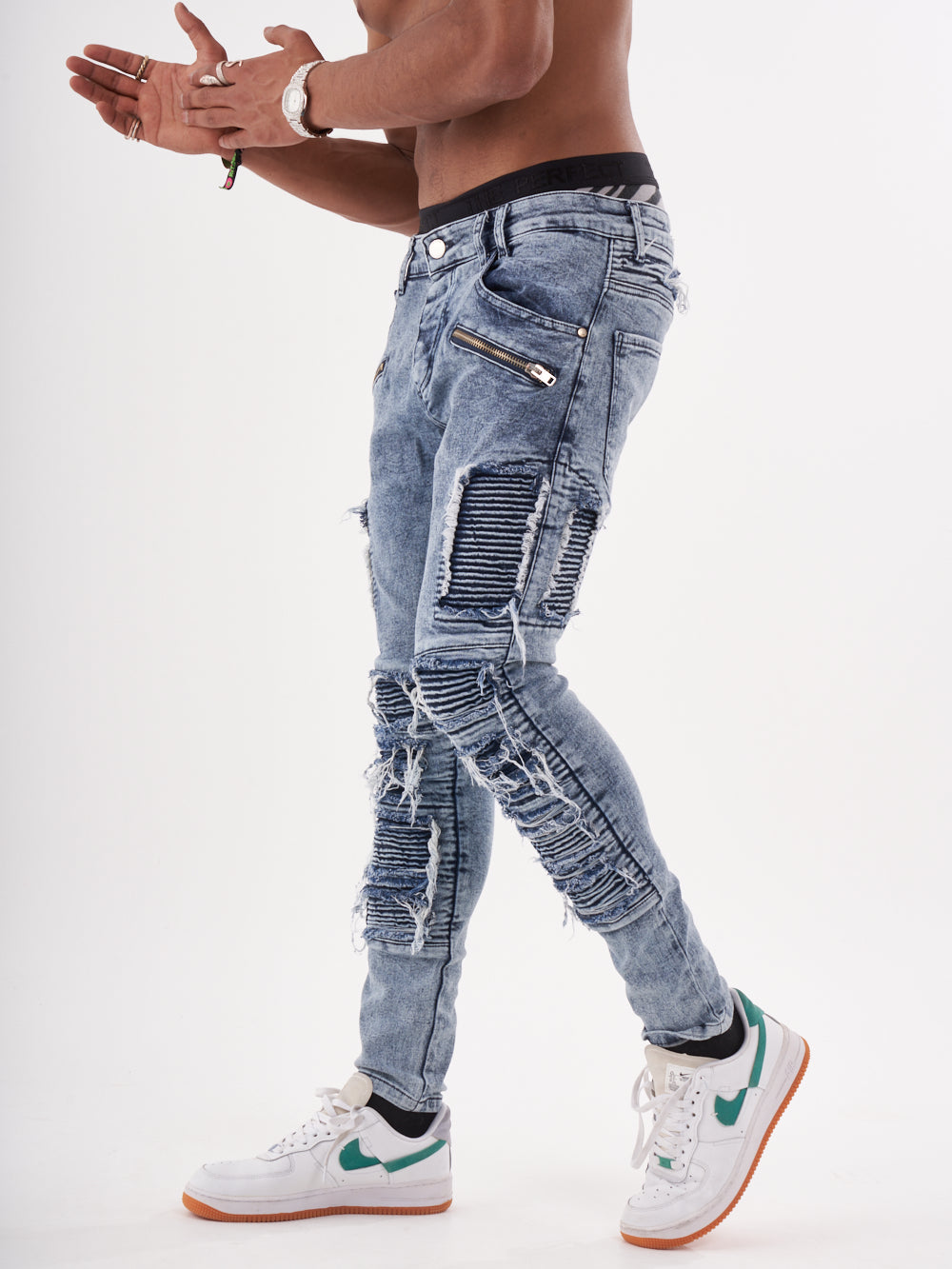 A man in RADICAL jeans and sneakers is standing on a white background.