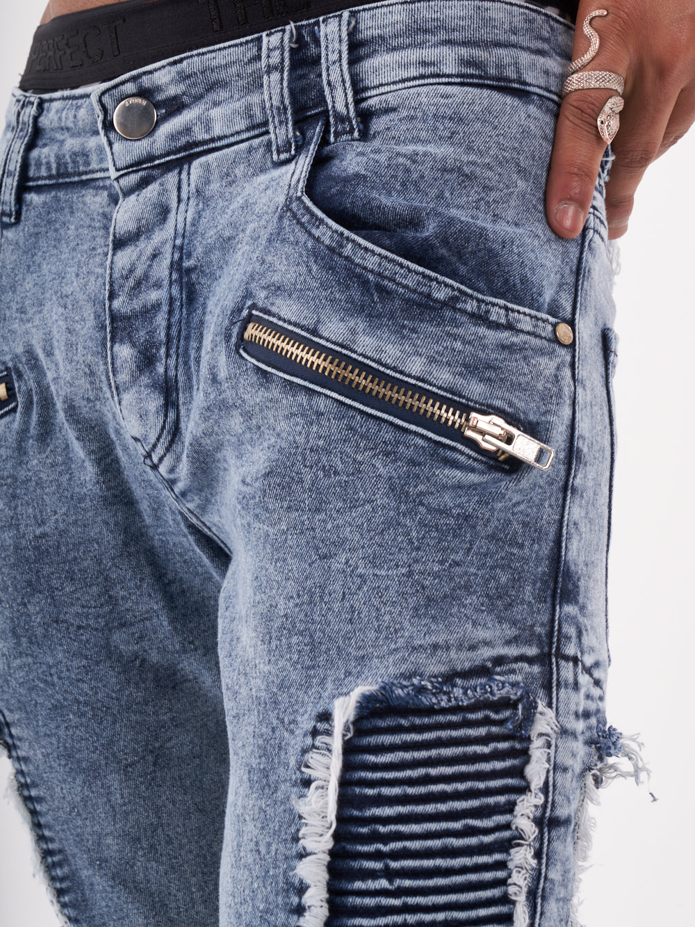 The back view of a man wearing RADICAL jeans with zippers.