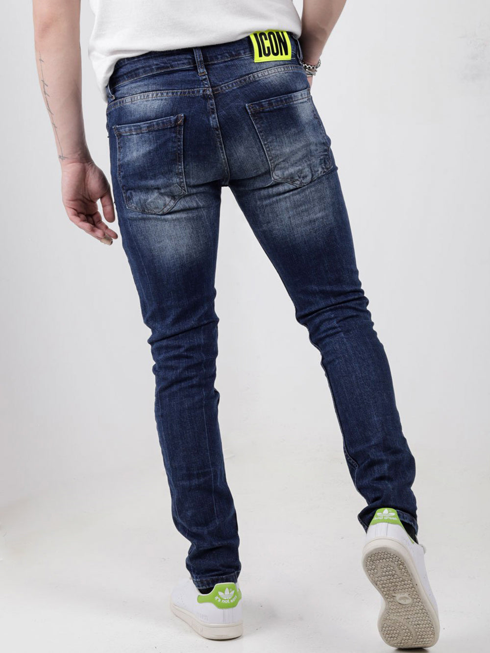 The back of a man wearing blue jeans and white sneakers PHOSPHORUS.
