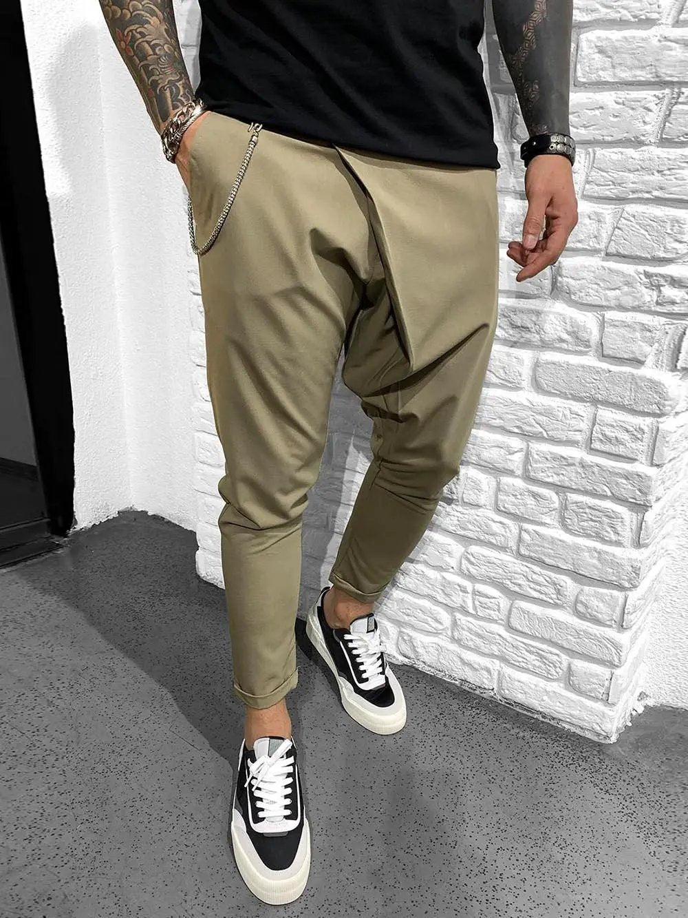 A man with tattoos wearing comfortable ASSYMMETRIC ROLL UP - MINK pants.